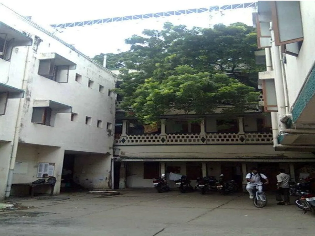 The inner courtyard between hostel blocks, motorcycles parked along one side and a large tree filling the upper half of the frame.