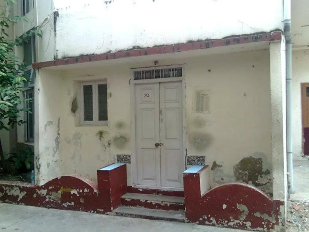 The panelled double door of number 20, its paint worn back to the wood, above a red-painted plinth and three shallow steps.